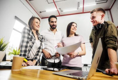 Gruppe von jungen Leuten in der Ausbildung am Schreibtisch vor Laptop