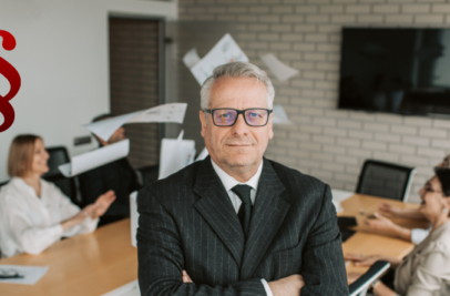 Ein älterer Herr im Anzug versinnbildlicht hier den CEO zum bildlichen Unterstreichen des Titels Geschäftsführerhaftung, im Hintergrund sitzen Mitarbeiter