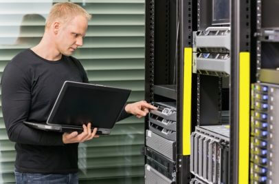 Techniker mit Notebook vor Rack Server