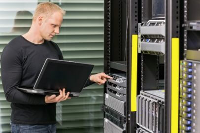 Senior IT-Techniker mit Notebook vor Rack Server 